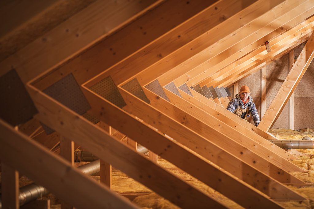 Inspector examining attic framing and insulation during home inspection services in Greenville, TX.